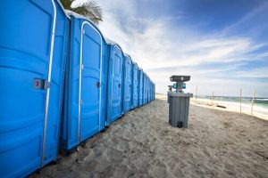 line of porta potties on the beach with a hand washing station